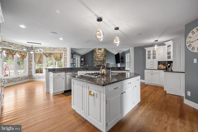 kitchen featuring white cabinetry, dishwasher, a center island, light hardwood / wood-style floors, and vaulted ceiling