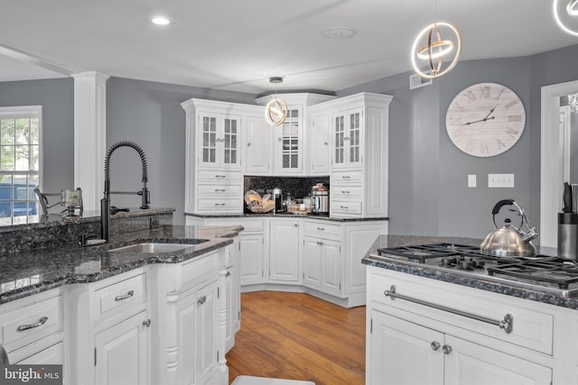 kitchen with decorative light fixtures, dark stone countertops, white cabinetry, and tasteful backsplash