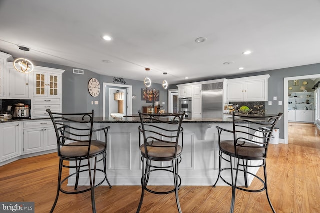 kitchen with backsplash, white cabinetry, and stainless steel built in fridge