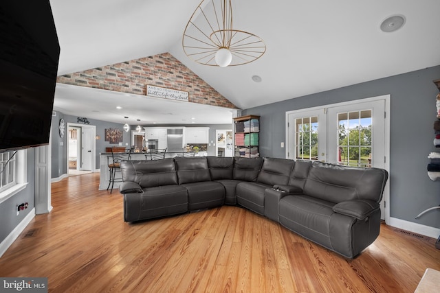 living room featuring french doors, light hardwood / wood-style flooring, and lofted ceiling