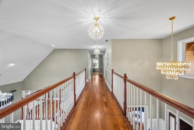 corridor featuring hardwood / wood-style floors, a notable chandelier, and vaulted ceiling