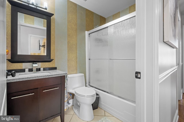 full bathroom featuring toilet, vanity, tile patterned floors, and bath / shower combo with glass door