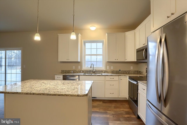 kitchen featuring white cabinets, appliances with stainless steel finishes, decorative light fixtures, and sink