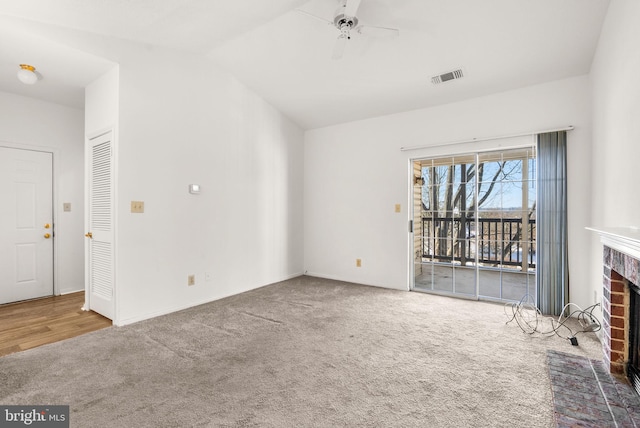 unfurnished living room with ceiling fan, carpet, lofted ceiling, and a fireplace