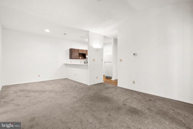 unfurnished living room featuring lofted ceiling and carpet flooring