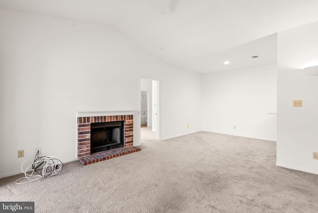 unfurnished living room with lofted ceiling, a brick fireplace, and carpet floors