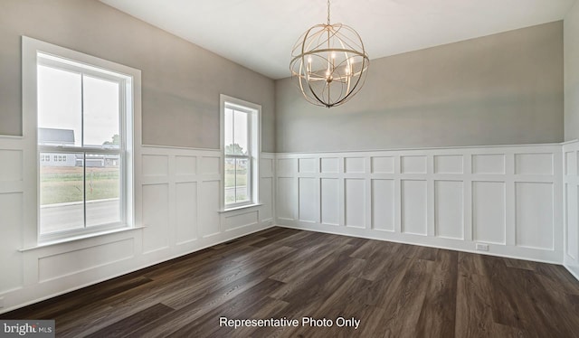 unfurnished dining area featuring a wealth of natural light, dark hardwood / wood-style flooring, and a notable chandelier