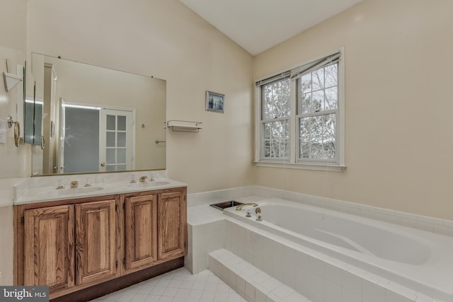 bathroom featuring lofted ceiling, vanity, tile patterned flooring, and a relaxing tiled tub