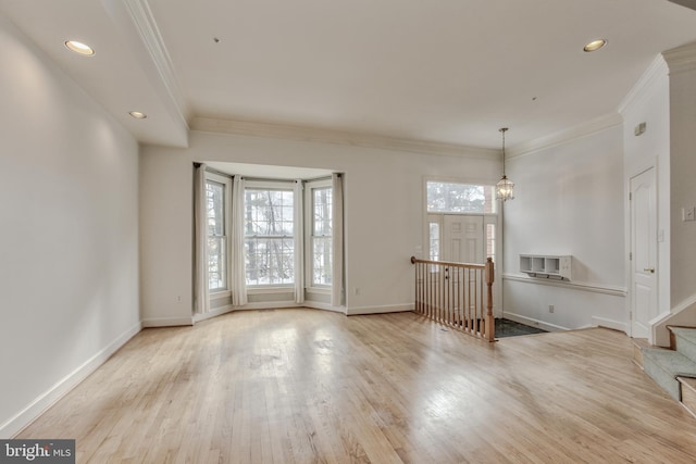 empty room featuring crown molding, an inviting chandelier, and light hardwood / wood-style floors