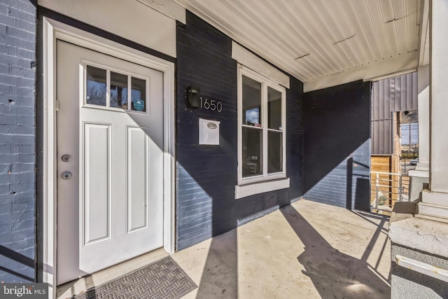 entrance to property with a porch and brick siding