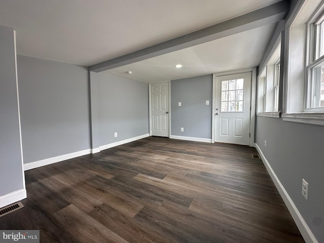 unfurnished room with beam ceiling and dark wood-type flooring