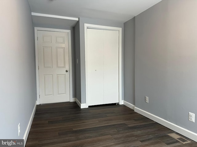 unfurnished bedroom featuring dark hardwood / wood-style floors and a closet