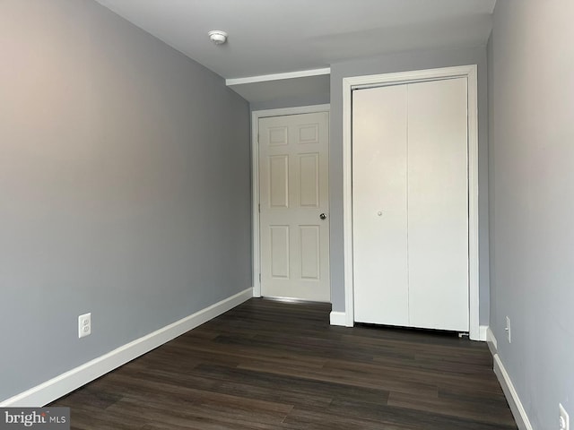 unfurnished bedroom featuring dark wood-type flooring and a closet