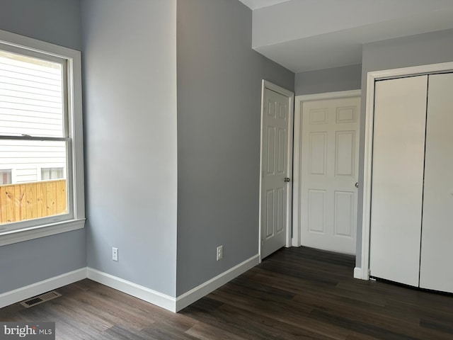 unfurnished bedroom featuring multiple windows and dark hardwood / wood-style floors