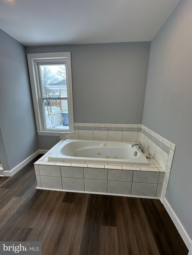 bathroom with tiled bath and hardwood / wood-style floors