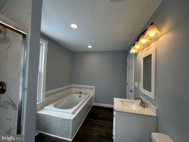 bathroom featuring vanity, a relaxing tiled tub, and hardwood / wood-style flooring