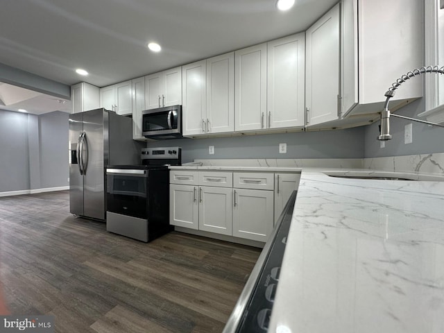 kitchen featuring light stone counters, white cabinets, stainless steel appliances, and dark hardwood / wood-style floors