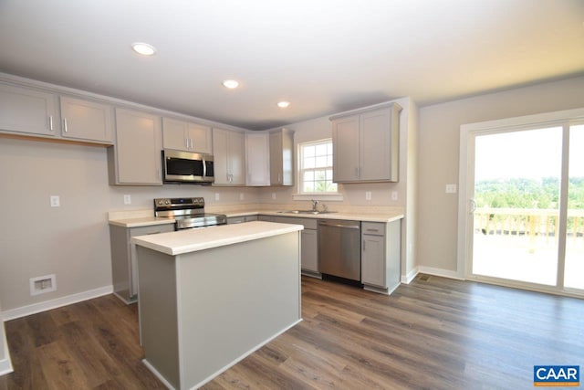 kitchen with appliances with stainless steel finishes, dark hardwood / wood-style flooring, a kitchen island, and gray cabinetry