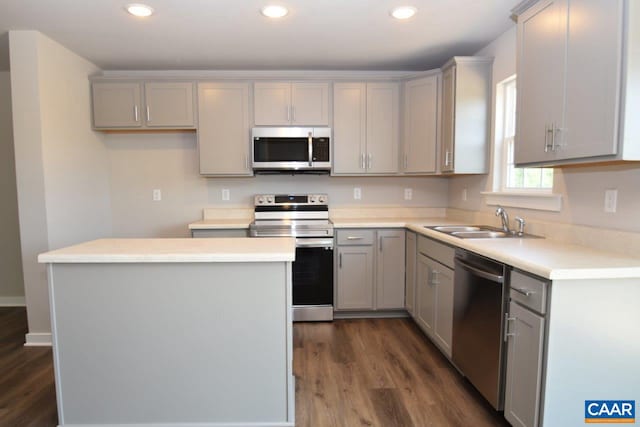 kitchen with appliances with stainless steel finishes, gray cabinetry, sink, a center island, and dark hardwood / wood-style floors