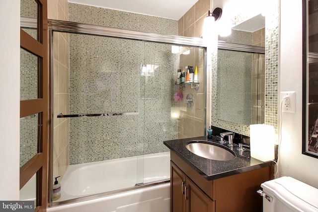 full bathroom with vanity, bath / shower combo with glass door, and toilet