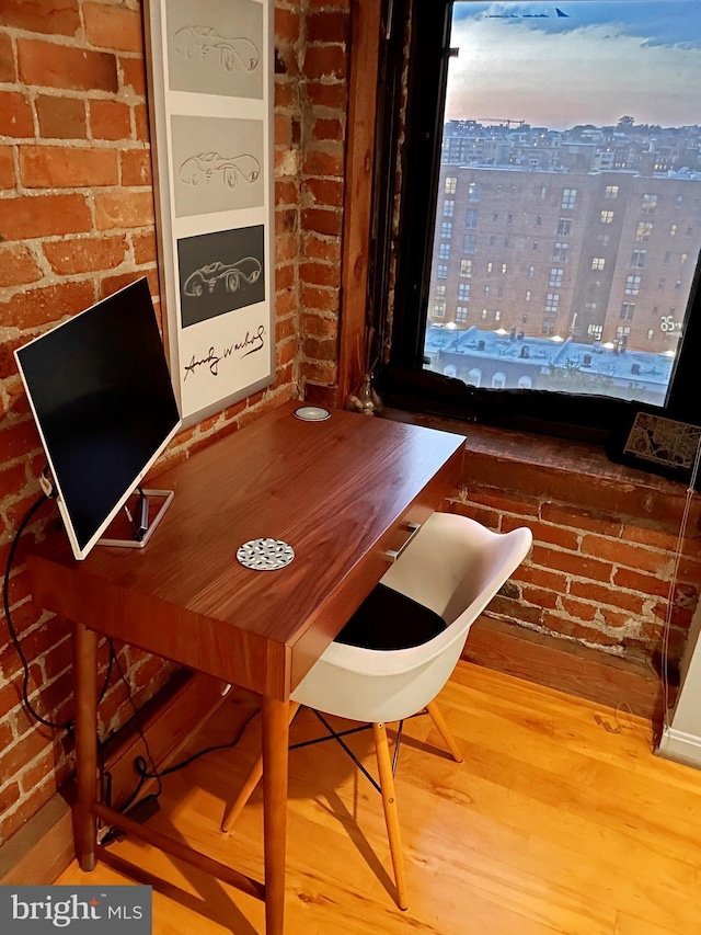 dining room featuring hardwood / wood-style floors and brick wall