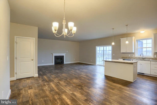 kitchen with white cabinetry, a center island, sink, a notable chandelier, and decorative light fixtures