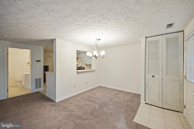 unfurnished dining area featuring light colored carpet, a textured ceiling, and an inviting chandelier