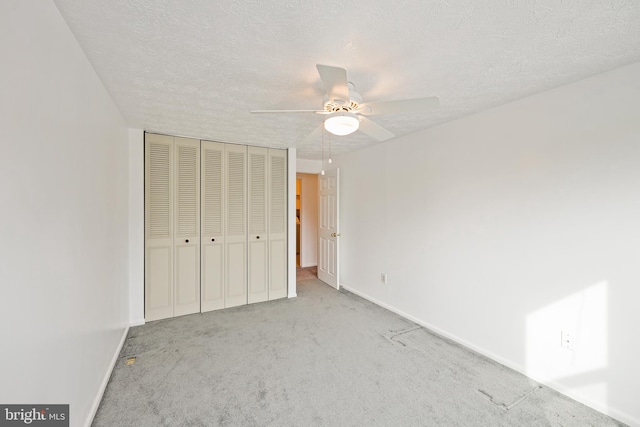 unfurnished bedroom featuring ceiling fan, light colored carpet, a textured ceiling, and a closet