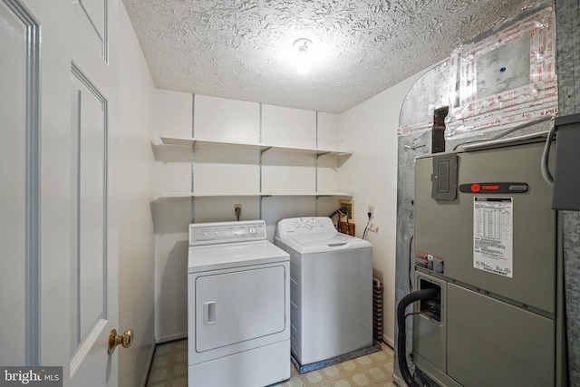 clothes washing area with washing machine and dryer and a textured ceiling