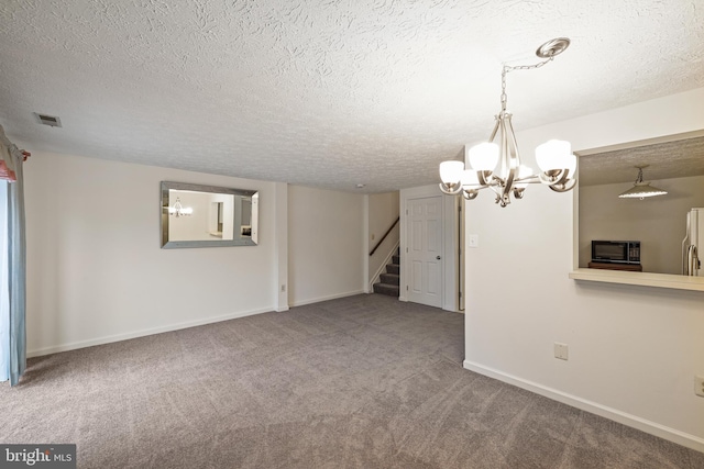 spare room featuring carpet floors, a textured ceiling, and an inviting chandelier