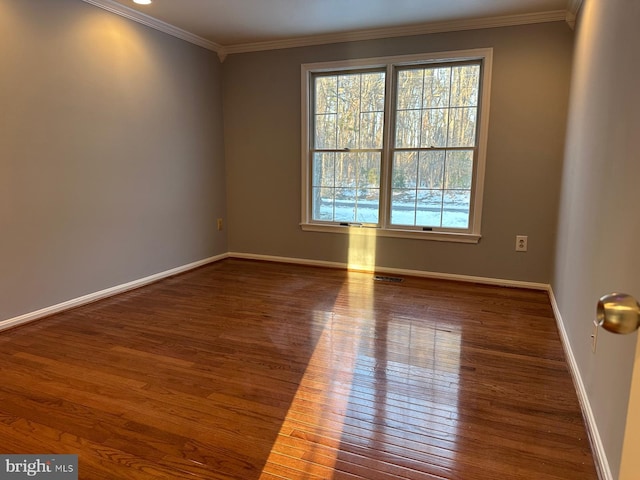 empty room featuring dark wood-type flooring and ornamental molding