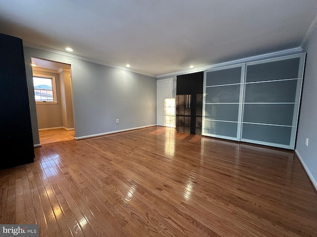 empty room with hardwood / wood-style flooring and ornamental molding