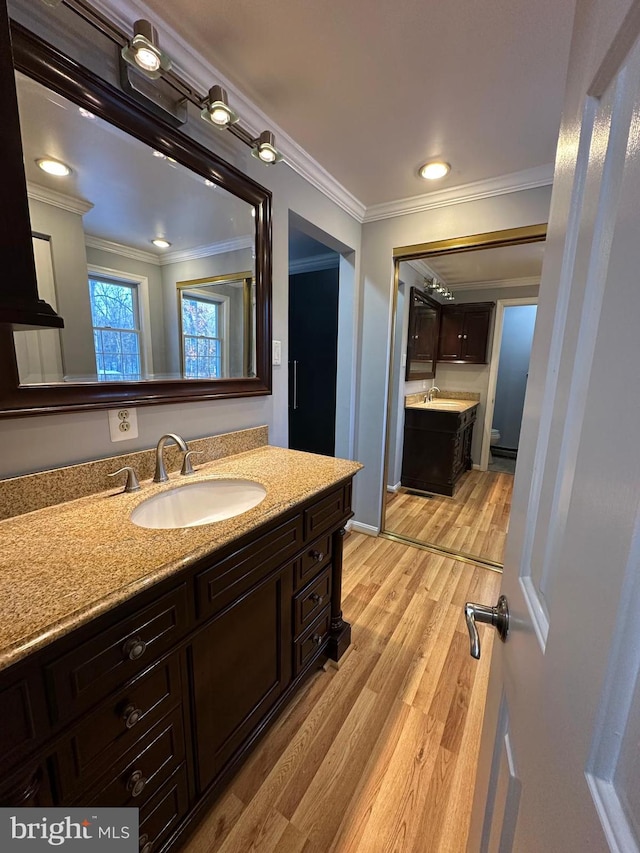 bathroom featuring wood-type flooring, toilet, vanity, and crown molding