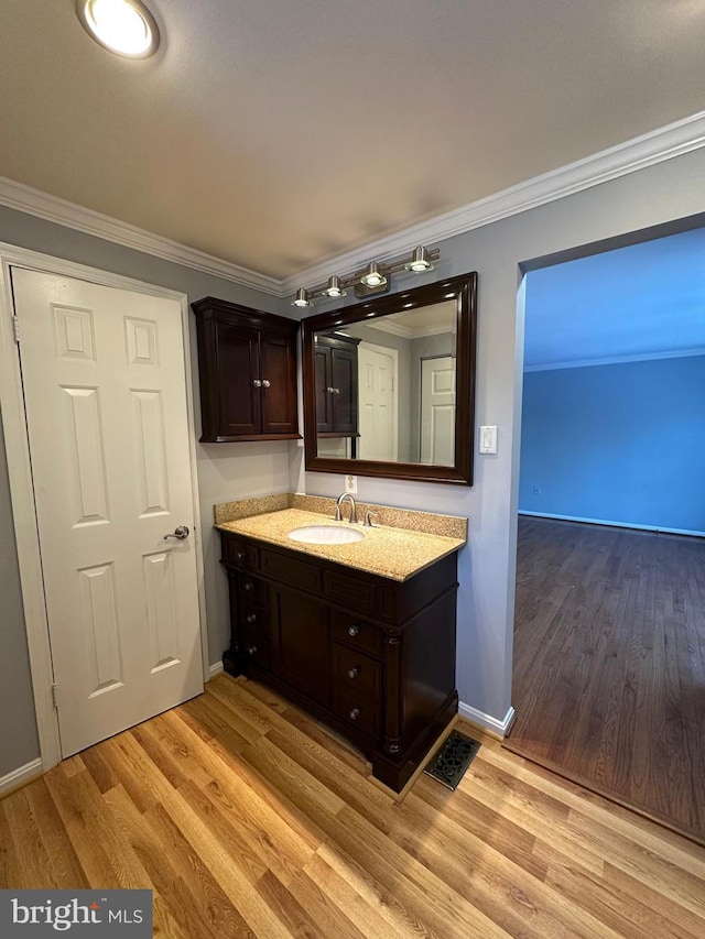 bathroom with wood-type flooring, vanity, and ornamental molding