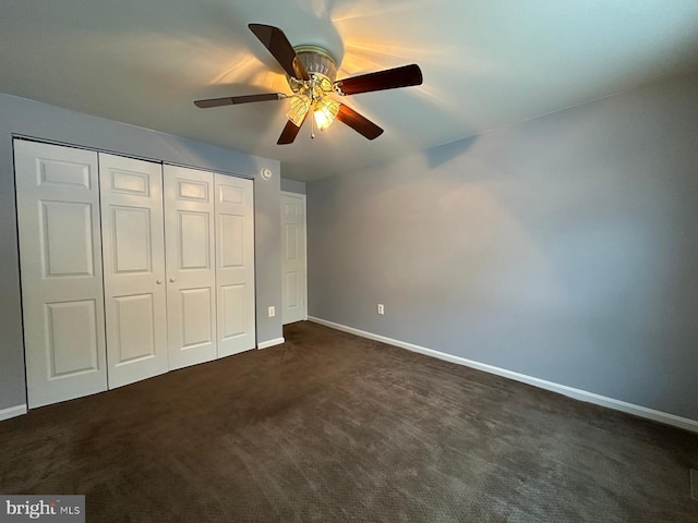 unfurnished bedroom with ceiling fan, a closet, and dark carpet