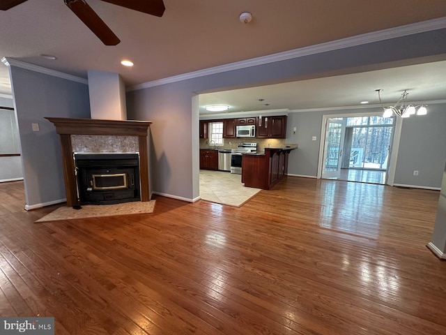 unfurnished living room featuring light wood-type flooring, crown molding, and ceiling fan with notable chandelier