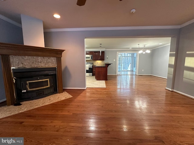 unfurnished living room with hardwood / wood-style flooring, crown molding, and a notable chandelier