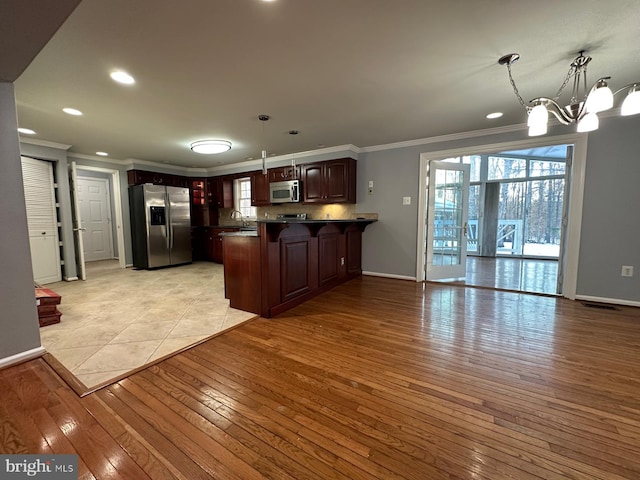 kitchen featuring decorative light fixtures, a chandelier, light wood-type flooring, and stainless steel appliances