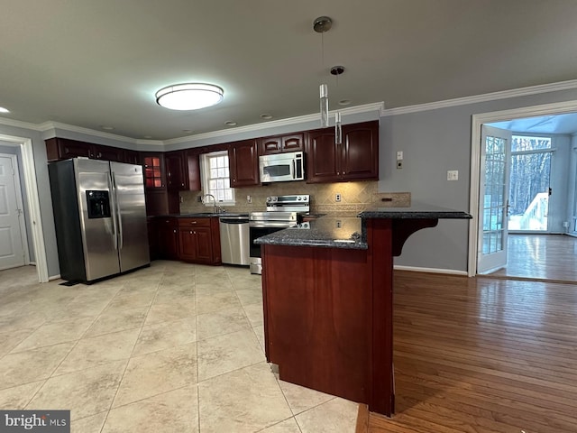 kitchen featuring stainless steel appliances, tasteful backsplash, decorative light fixtures, crown molding, and sink