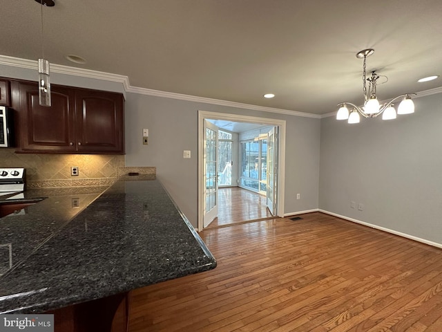 kitchen featuring backsplash, hanging light fixtures, a notable chandelier, light hardwood / wood-style flooring, and dark brown cabinets