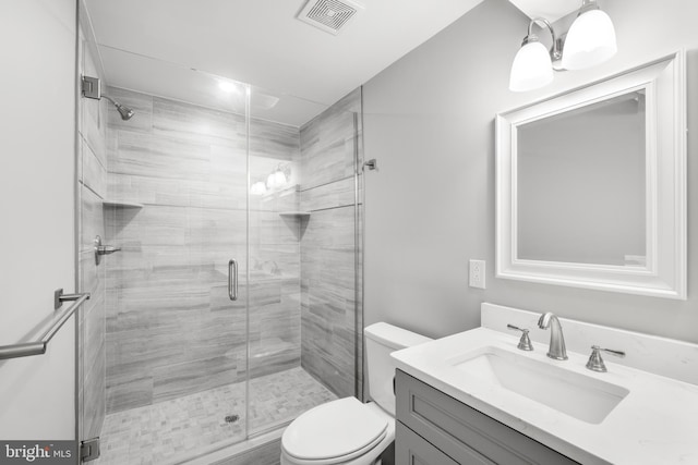 bathroom with vanity, a shower with shower door, and toilet