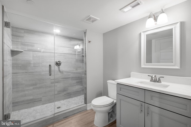 bathroom with hardwood / wood-style floors, vanity, toilet, and an enclosed shower