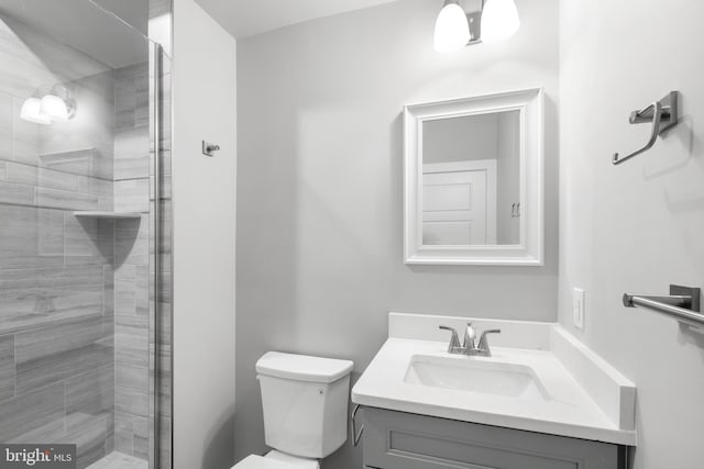 bathroom with vanity, toilet, and a shower with door