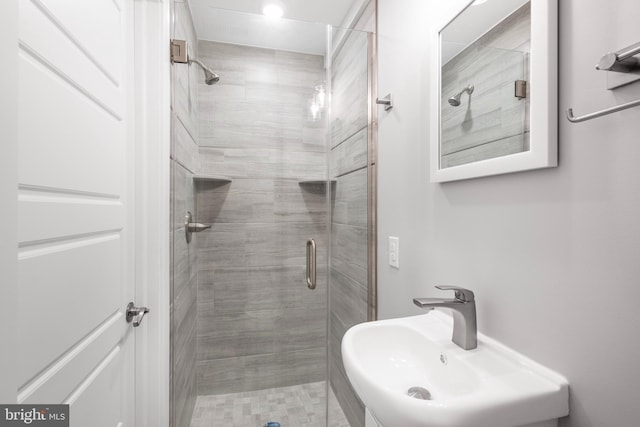 bathroom with a shower with door and sink