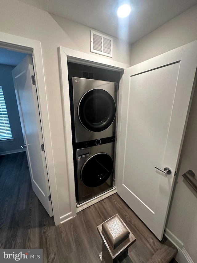 laundry room featuring dark hardwood / wood-style flooring and stacked washer and dryer