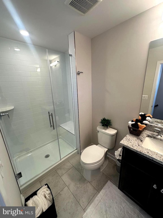 bathroom featuring tile patterned floors, vanity, a shower with shower door, and toilet