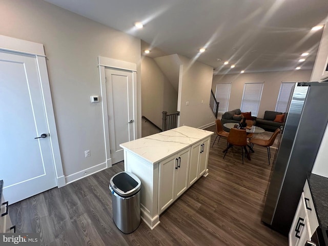 kitchen featuring dark hardwood / wood-style flooring, light stone countertops, a center island, and white cabinets