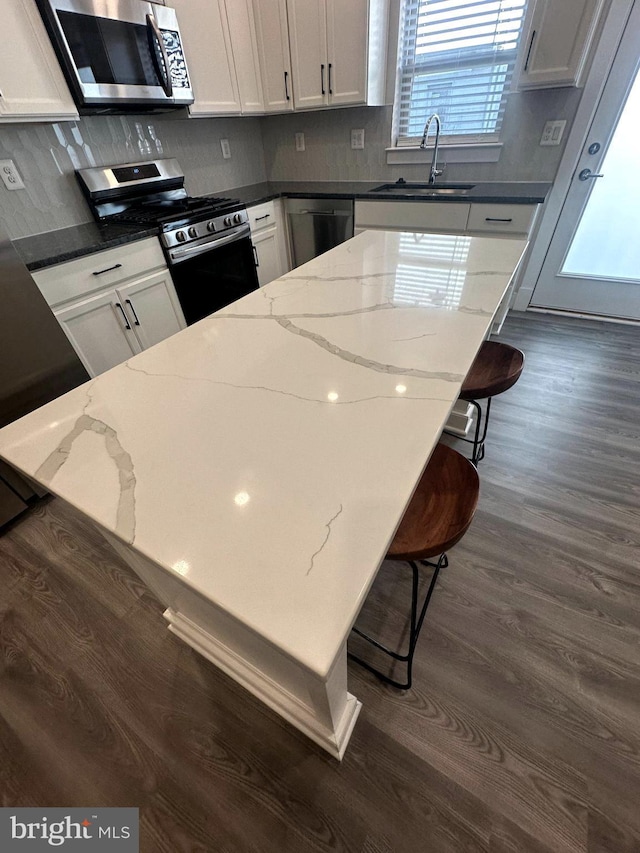 kitchen featuring a kitchen bar, appliances with stainless steel finishes, white cabinets, and sink