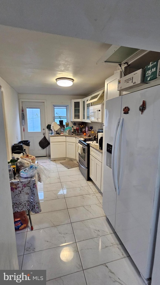 kitchen featuring backsplash, white cabinets, and white appliances