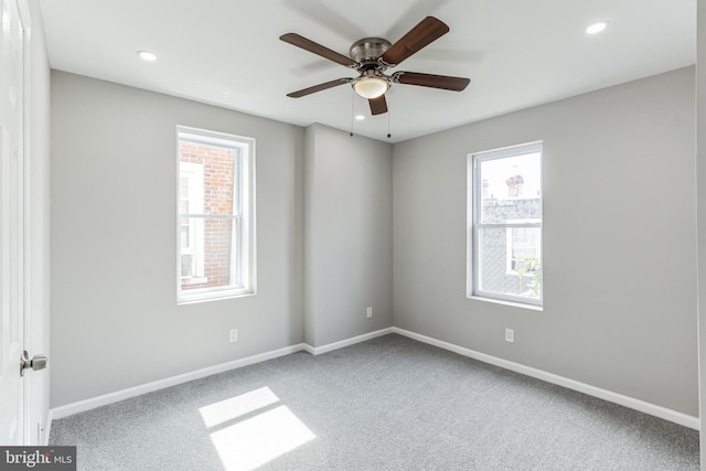 carpeted spare room featuring plenty of natural light and ceiling fan